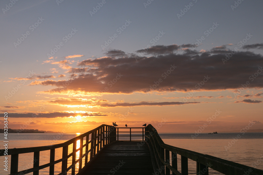 Fototapeta premium Silhouette of a romantic pier at sunrise as sea holidays concept