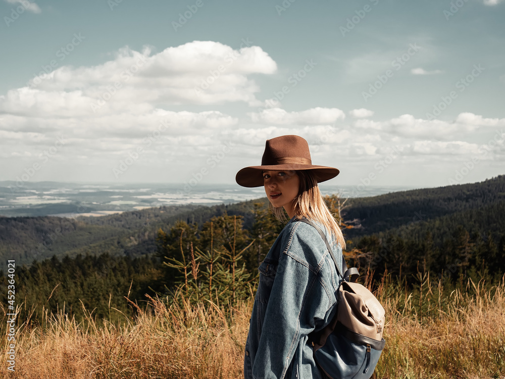 Woman in hat looking on nature, forest and clouds