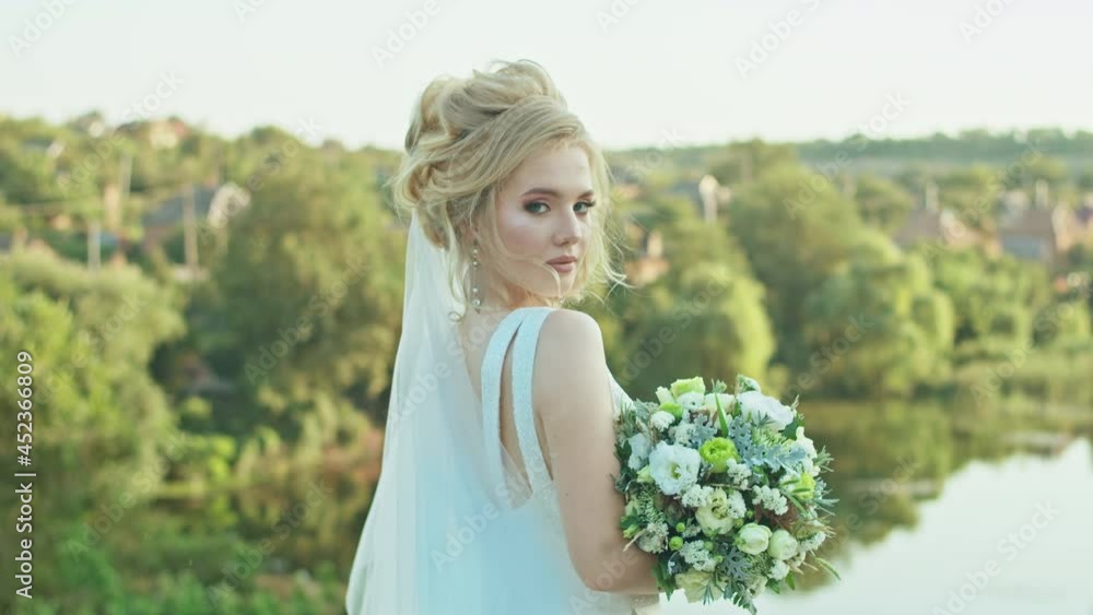 happy young woman bride with a wedding bouquet stands on the background of the river, happy young woman bride with a wedding bouquet stands on the background of the river,