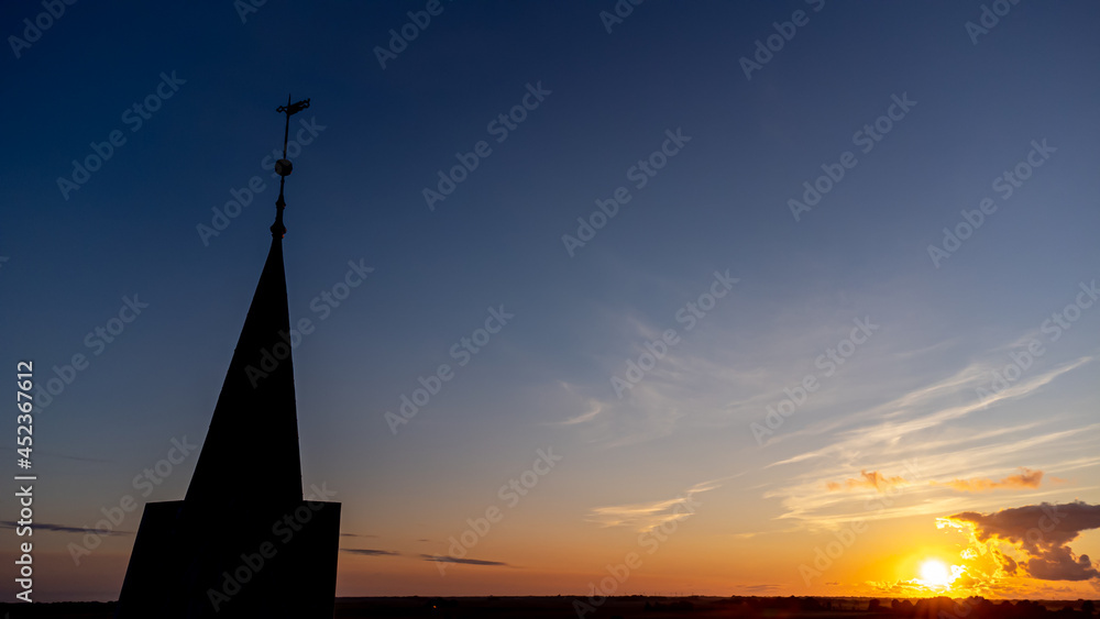 Obraz premium Kirche und Kirchturm im Sonnenuntergang mit weiter Landschaft und Natur im Hintergrund