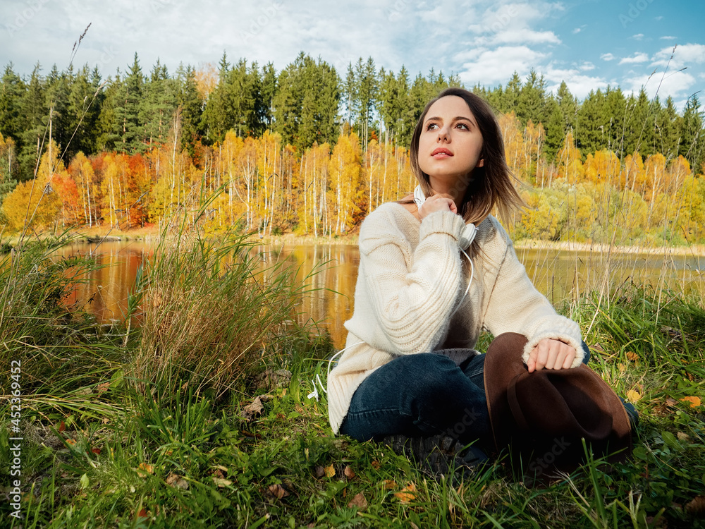 woman with headphones near lake in autumn time