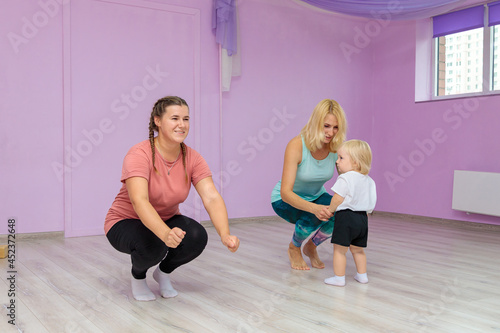 Mom and baby are doing exercises with an instructor in the gym. Developmental exercises for the baby.
