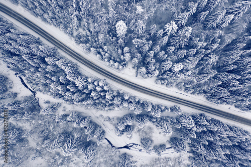 Road in the winter mountain forest. Drone view.