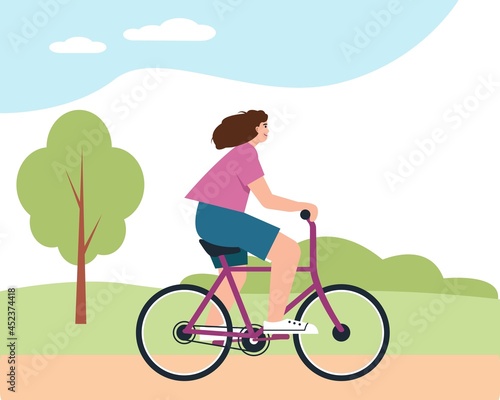 Young woman on bycicle in park. Smiling happy girl rides bike.