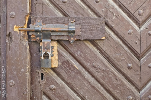 Old wooden gate closed with a padlock