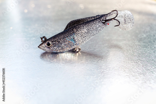 Silver sparkly fish bait plastic hook on a light grey background