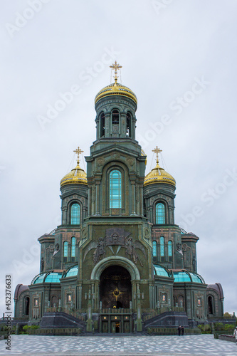 KUBINKA, MOSCOW REGION, RUSSIA-AUGUST, 22, 2021: the facade of the modern main temple of the Russian Armed Forces with golden domes in Patriot Park against a blue cloudy sky