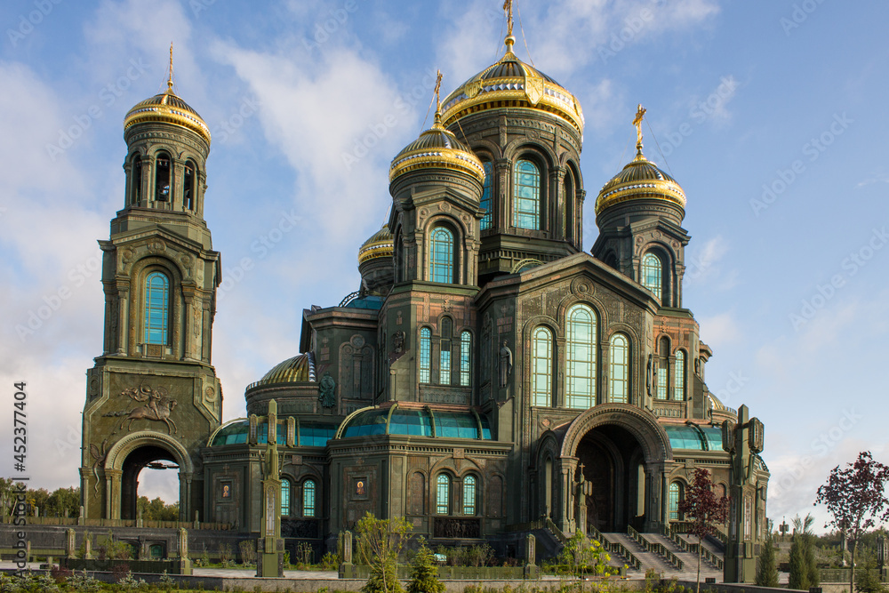 facade of the modern main temple of the Russian Armed Forces with golden domes in Patriot Park against a blue cloudy sky in Kubinka Moscow region