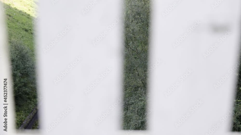 A view of train tracks through a white fence. Close up shot looking through the gaps in the fence for an abstract look. A view of train tracks through a white fence. Close up shot looking through the gaps in the fence for an abstract look.