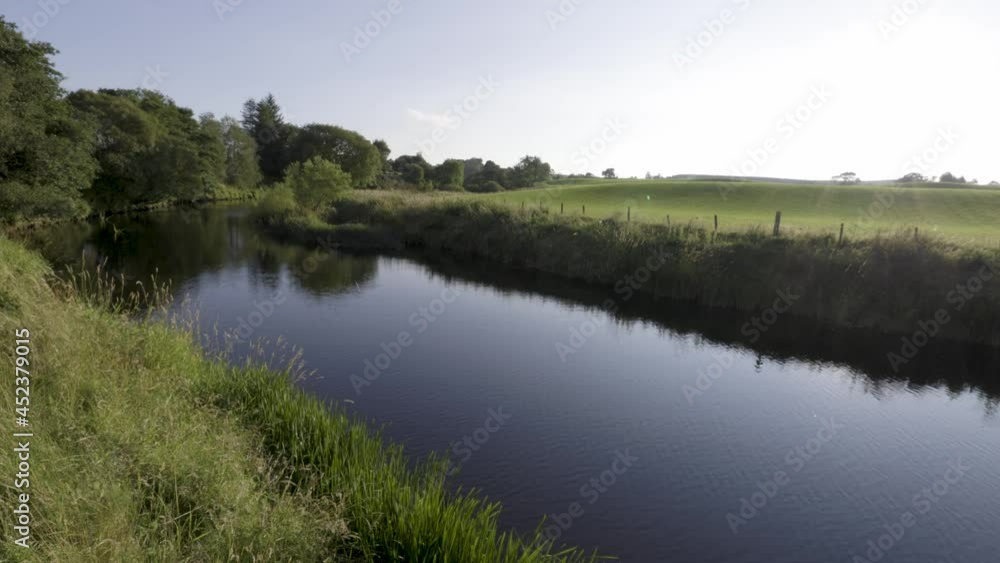 Calm river flowing through green fields in the countryside on a warm, summers day. Calm river flowing through green fields in the countryside on a warm, summers day.