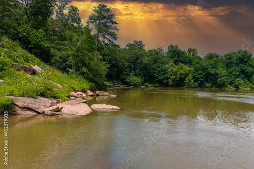 a stunning shot of the silky brown waters of the Chattahoochee river with vast miles of lush green trees along the river with powerful clouds at McIntosh Reserve Park in Whitesburg Georgia photo