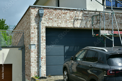 Moderne Einbau-Garage mit Automatik-Rolltor und darüber angeordneter Dachterrasse/Wintergarten, angebaut an ein modernes Einfamilienhaus
