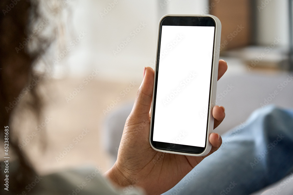 Young woman hands holding cell phone with mockup white blank display, empty screen for app ads at home. Delivery and shopping mobile applications technology concept, over shoulder close up view. Young woman hands holding cell phone with mockup white blank display, empty screen for app ads at home. Delivery and shopping mobile applications technology concept, over shoulder close up view.