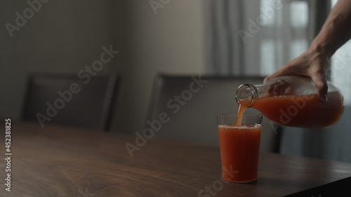 pour grafruit juice into tumbler glass on walnut table photo