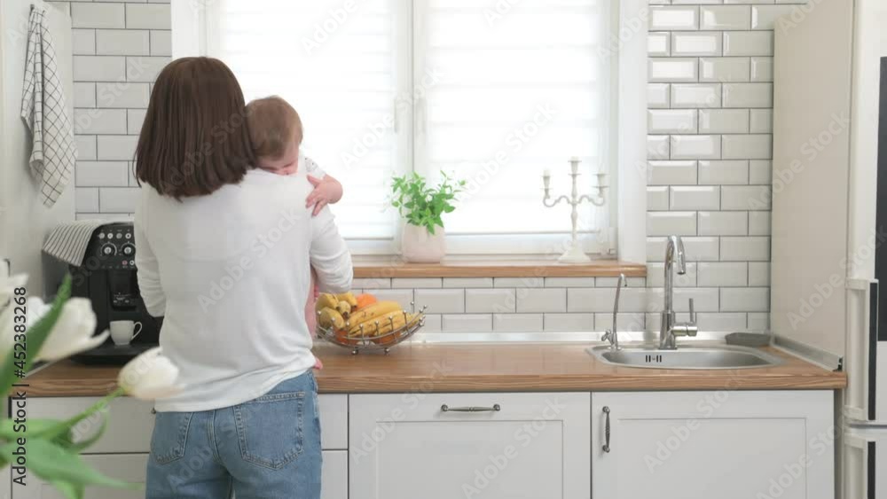 Mother with an infant in a white kitchen Mother with an infant in a white kitchen
