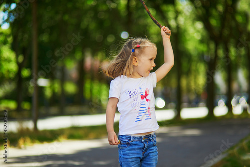 Adorable preschooler girl playing with a stick