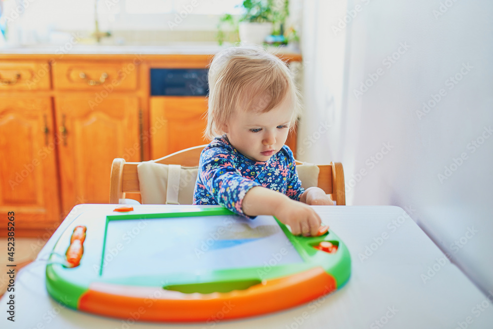 Adorable little girl drawing on magnetic magic screen Adorable little girl drawing on magnetic magic screen