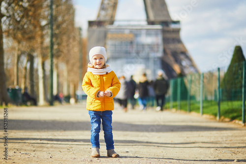 Adorable toddler girl walking near the Eiffel tower in Paris, France