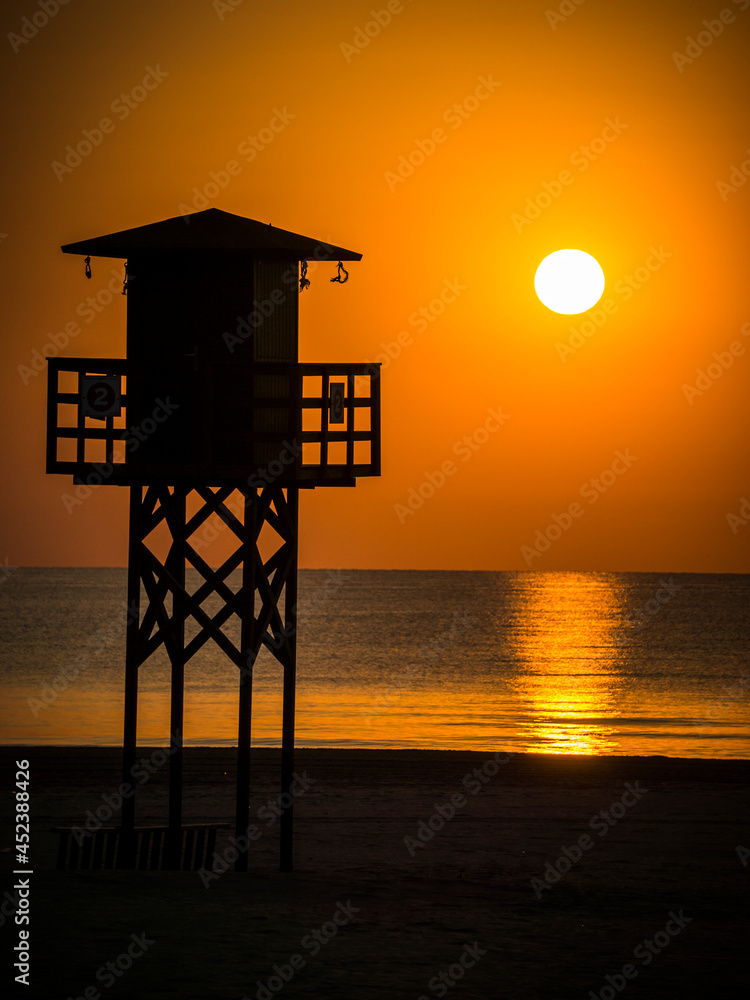 Watchtower for lifeguards on a Valencia beach with the sun in the background at sunrise