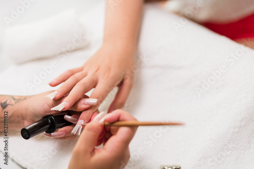 Brasilian latin mid woman manicure profesional puting to a cliente fiberglass nails autumn evoque