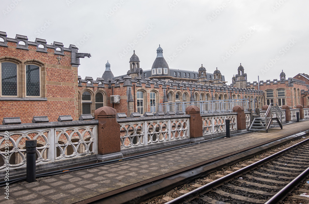 Gent, Flanders, Belgium - August 1, 2021: Back side of Sint Pieters railway station shows historic red brick building with gray stone trim, as seen from the tracks.