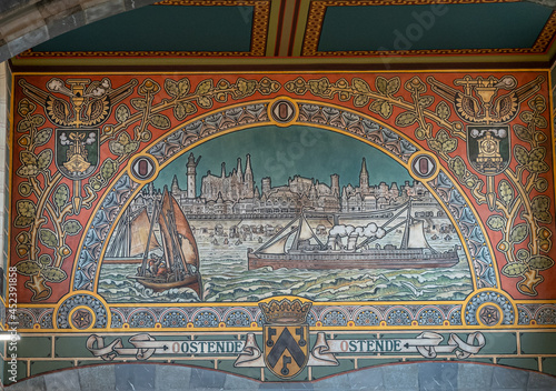 Gent, Flanders, Belgium - August 1, 2021: Painting skyline of Oostende city on wall of central entrance hall of Sint Pieters Railway Station. Beach and boats as coastal town. photo