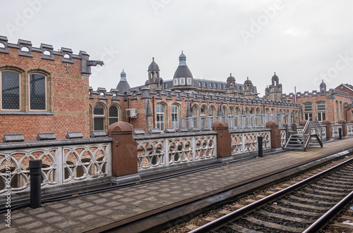 Gent, Flanders, Belgium - August 1, 2021: Back side of Sint Pieters railway station shows historic red brick building with gray stone trim, as seen from the tracks. photo