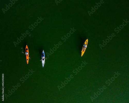 Aerial photograph, taken with a drone, looking down on three kayakers as they paddle across the green waters of the Telco Reservoir.
