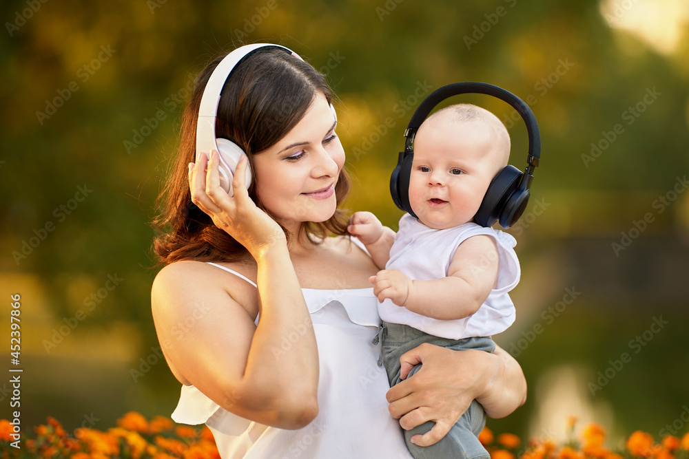 Woman with baby in wireless headphones outside. Woman with baby in wireless headphones outside.