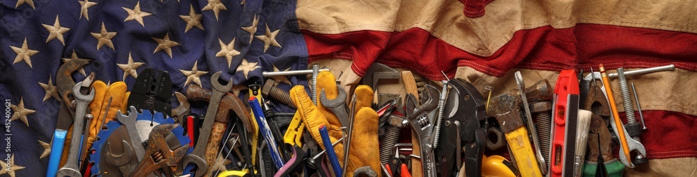 Patriotic collection of old and used work tools on worn US American flag. Made in USA, American workforce, or Labor Day concept.