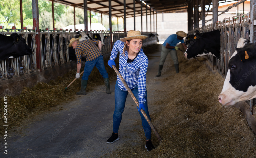 Portrait of active female employee working in cowshed on farm