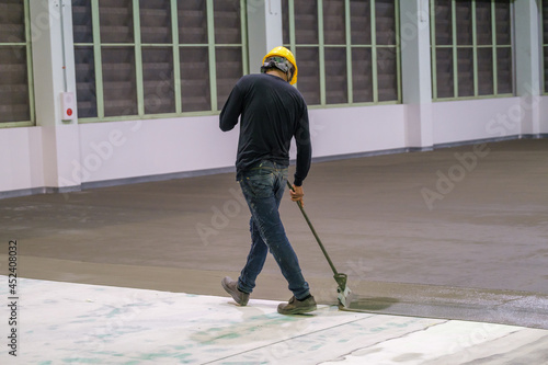 Construction worker using trowel spreading moisture blocking epoxy primer for Self-leveling method of epoxy floor finishing work