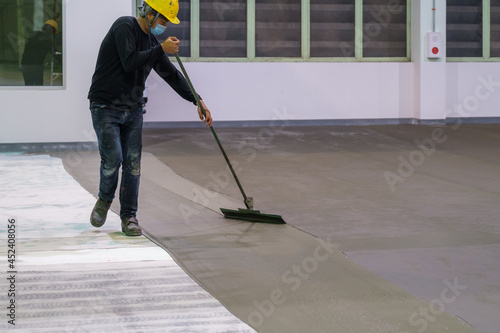 Construction worker using trowel spreading moisture blocking epoxy primer for Self-leveling method of epoxy floor finishing work