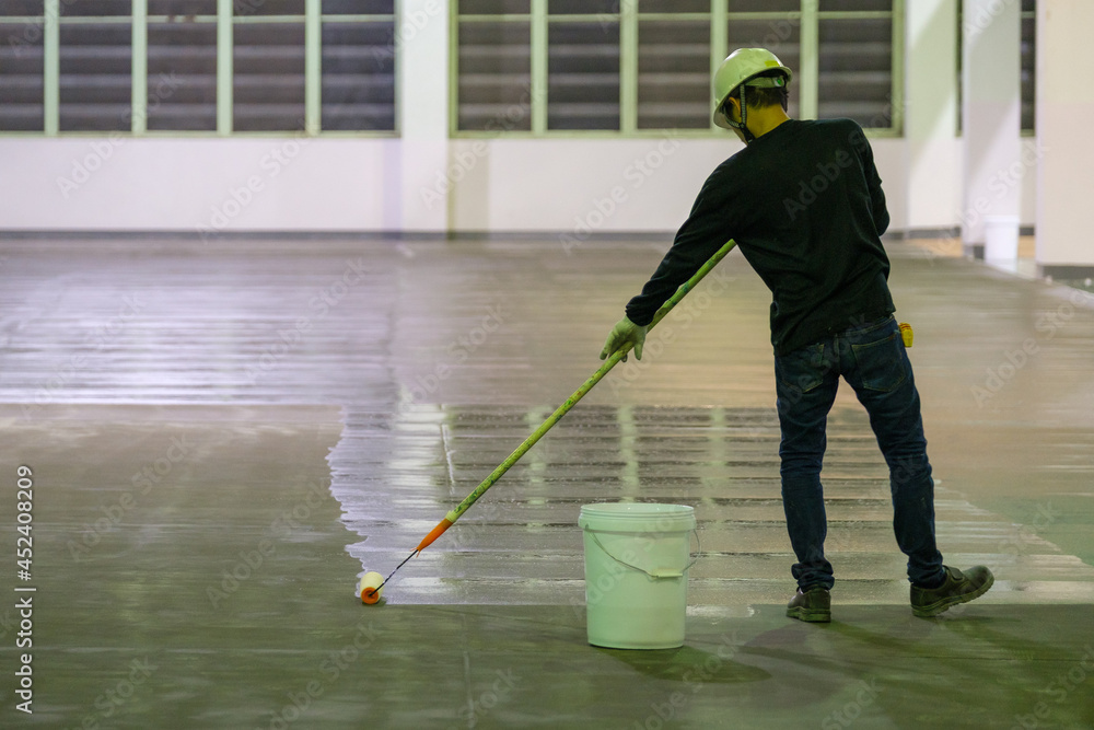 Construction worker using rollor spreading epoxy primer for Self