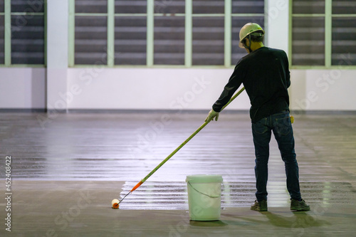 Construction worker using rollor spreading epoxy primer for Self-leveling method of epoxy floor finishing work