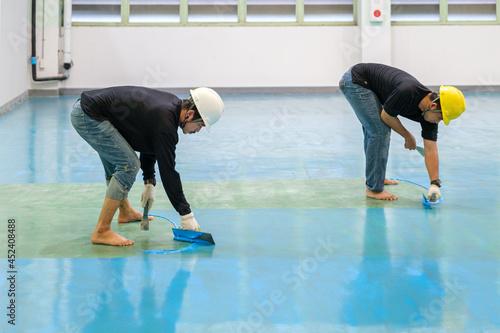Construction workers are using trowel spreading epoxy putty for Self-leveling method of epoxy floor finishing work