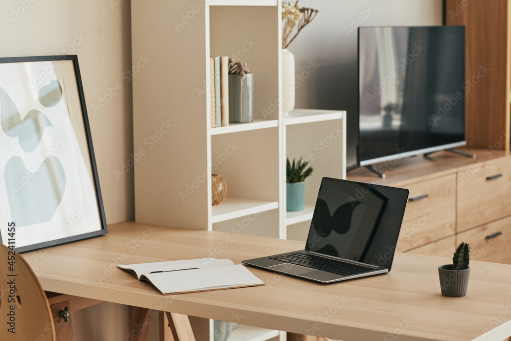 Background image of minimal home office setup with blank laptop on wooden desk in cozy apartment, copy space Background image of minimal home office setup with blank laptop on wooden desk in cozy apartment, copy space