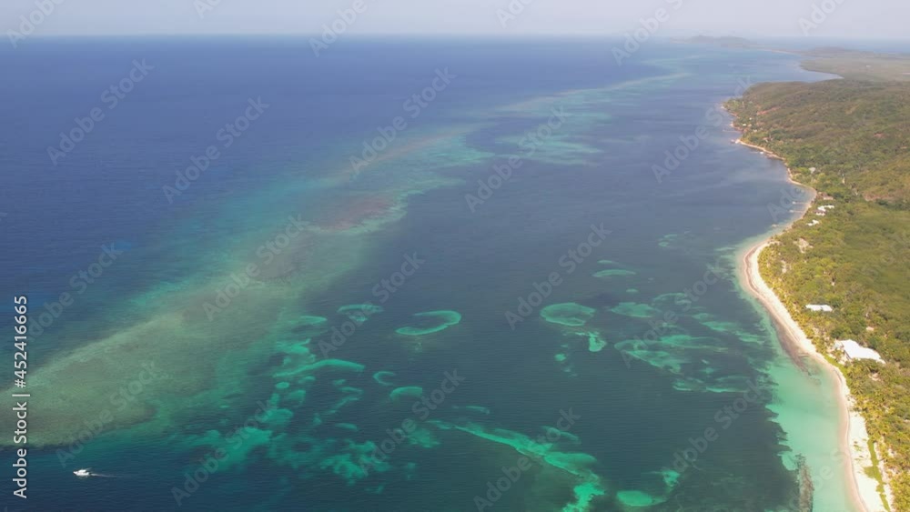 Aerial fooage of amazing tropical white sand beach and turquoise clear sea water with small waves and palm trees forest. Roatan island, Atlantida, Honduras. Caribbean. Travel tropical concept. Aerial fooage of amazing tropical white sand beach and turquoise clear sea water with small waves and palm trees forest. Roatan island, Atlantida, Honduras. Caribbean. Travel tropical concept.