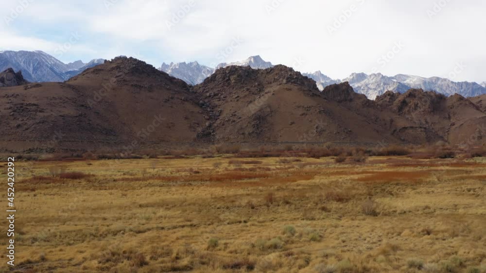 Aerial Over Dry Desert Grasslands At Eastern Sierra With Mountains In Distance. Dolly Back Aerial Over Dry Desert Grasslands At Eastern Sierra With Mountains In Distance. Dolly Back