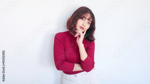 Thinking gesture of Asian beautiful girl with red shirt in white background © Reezky