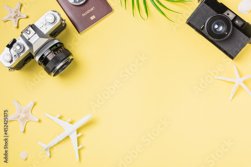 Flat lay top view mockup retro camera films, airplane, leaves, starfish traveler tropical beach accessories on a yellow background with copy space, Vacation summer travel and business trip concept