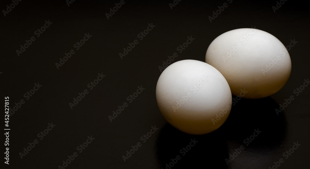 Two white eggs on a dark background with copy space Two white eggs on a dark background with copy space
