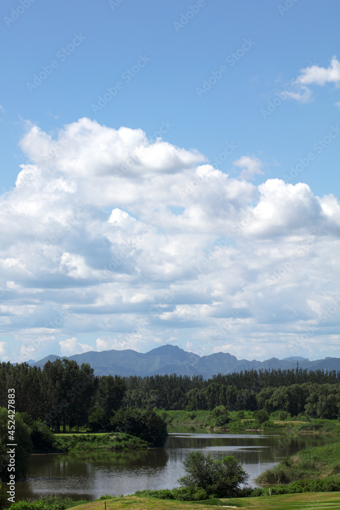 Obraz premium Green hills green water blue sky white clouds