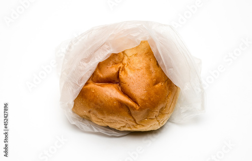 A delicious hamburger bun inside of a transparent polybag on white background