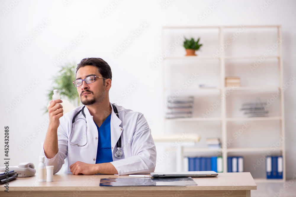 Young male doctor suggesting pills in the clinic