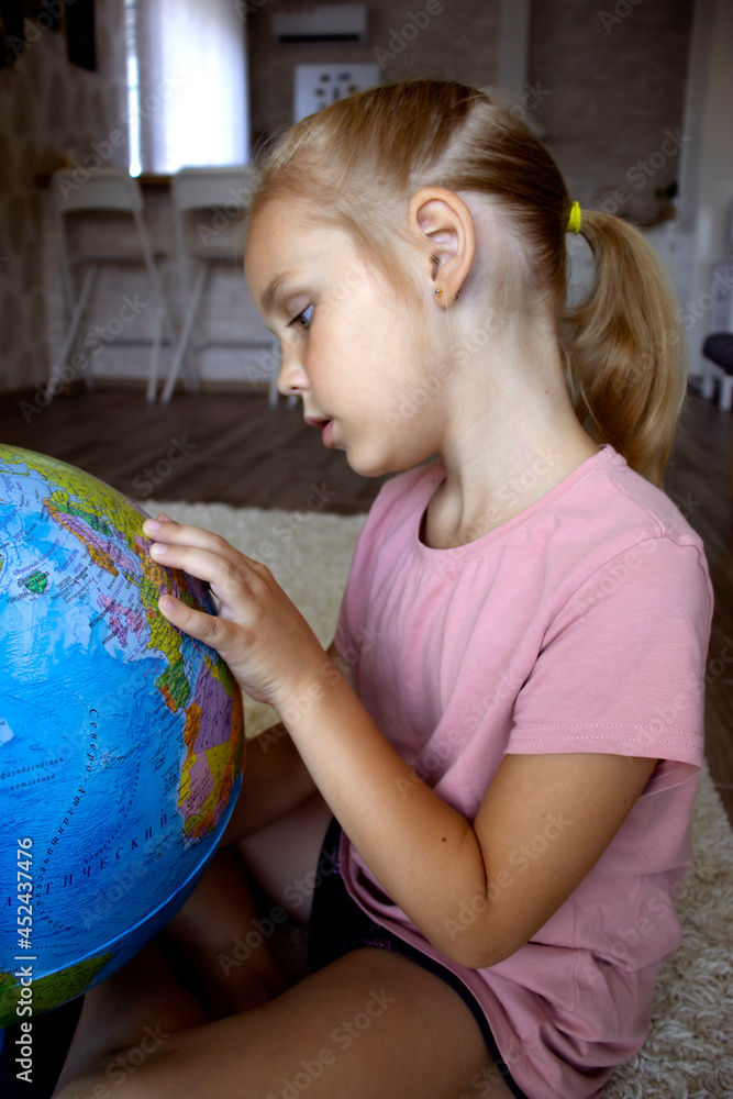 cute girl 7 years old of European appearance with blue eyes and blond hair hugs the globe, plays with a paper plane, early education through the game cute girl 7 years old of European appearance with blue eyes and blond hair hugs the globe, plays with a paper plane, early education through the game