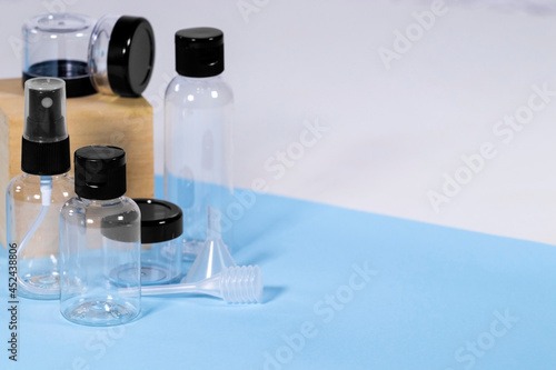Group of Plastic clear travelling bottles for Cosmetic: soap, gel, lotion, cream, shampoo, make up and liquids on light blue Background. Modern Traveling Concept. Copy Space. Container for carryon.