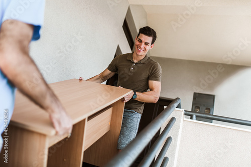 Man Movers Carrying Table On Staircase Of House photo
