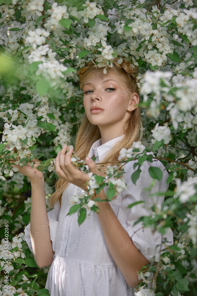 Romantic portrait of a girl in the park near a blooming apple tree. Natural cosmetics. Natural beauty of a woman in a white dress Romantic portrait of a girl in the park near a blooming apple tree. Natural cosmetics. Natural beauty of a woman in a white dress