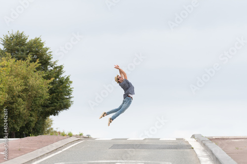 Young happy man jumping while crossing the road in the horizon. Happiness concept with copy space. Minimal composition © Egoitz
